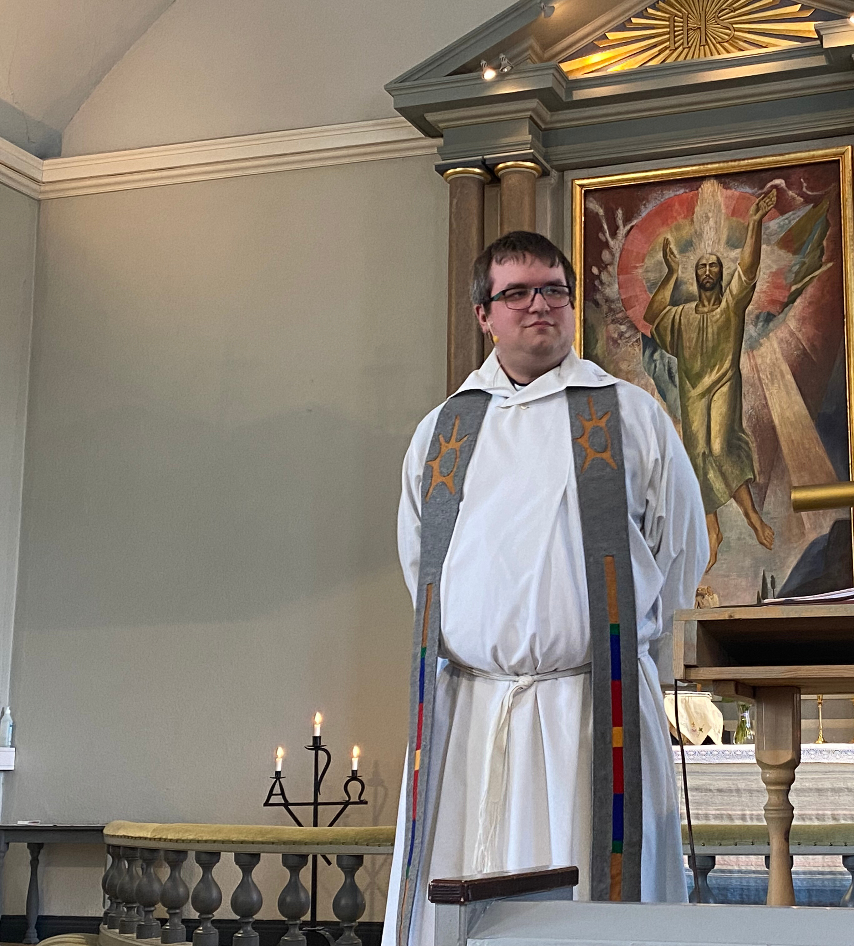 En präst står i en kyrka. Över axlarna bär han en stola med samiska mönster.