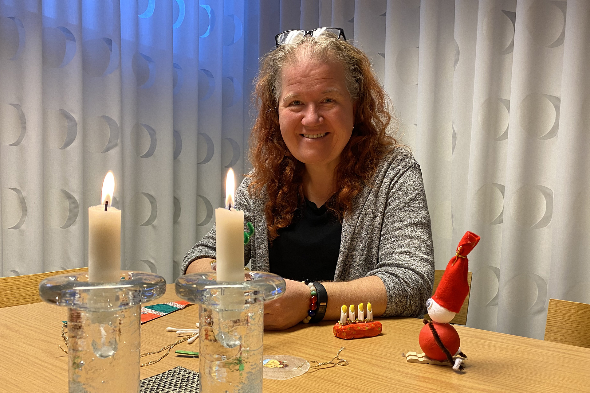 Anna Karlsson julpysslar vid två tända ljusstakar. 