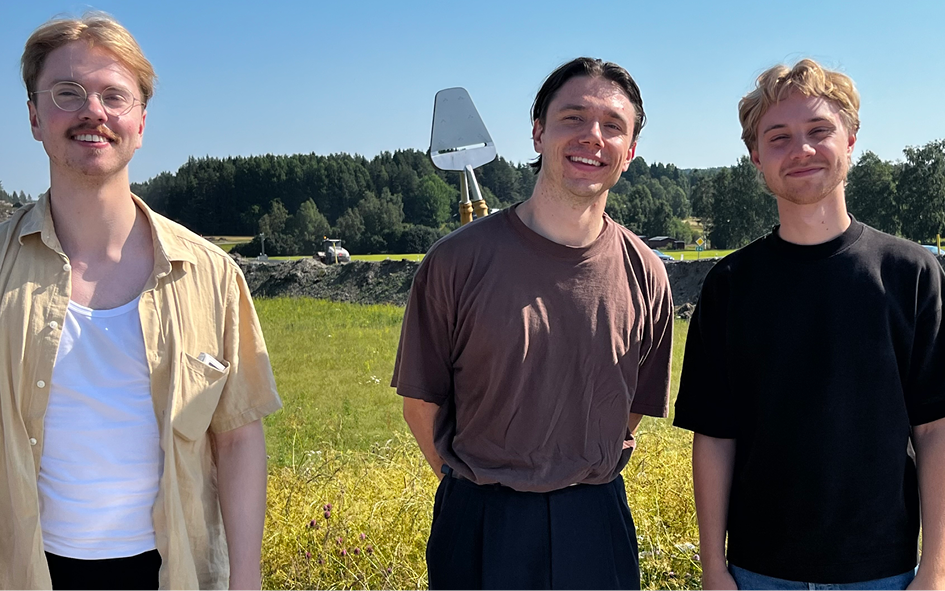Tre glada unga herrar i gröngräset en solig sommardag.