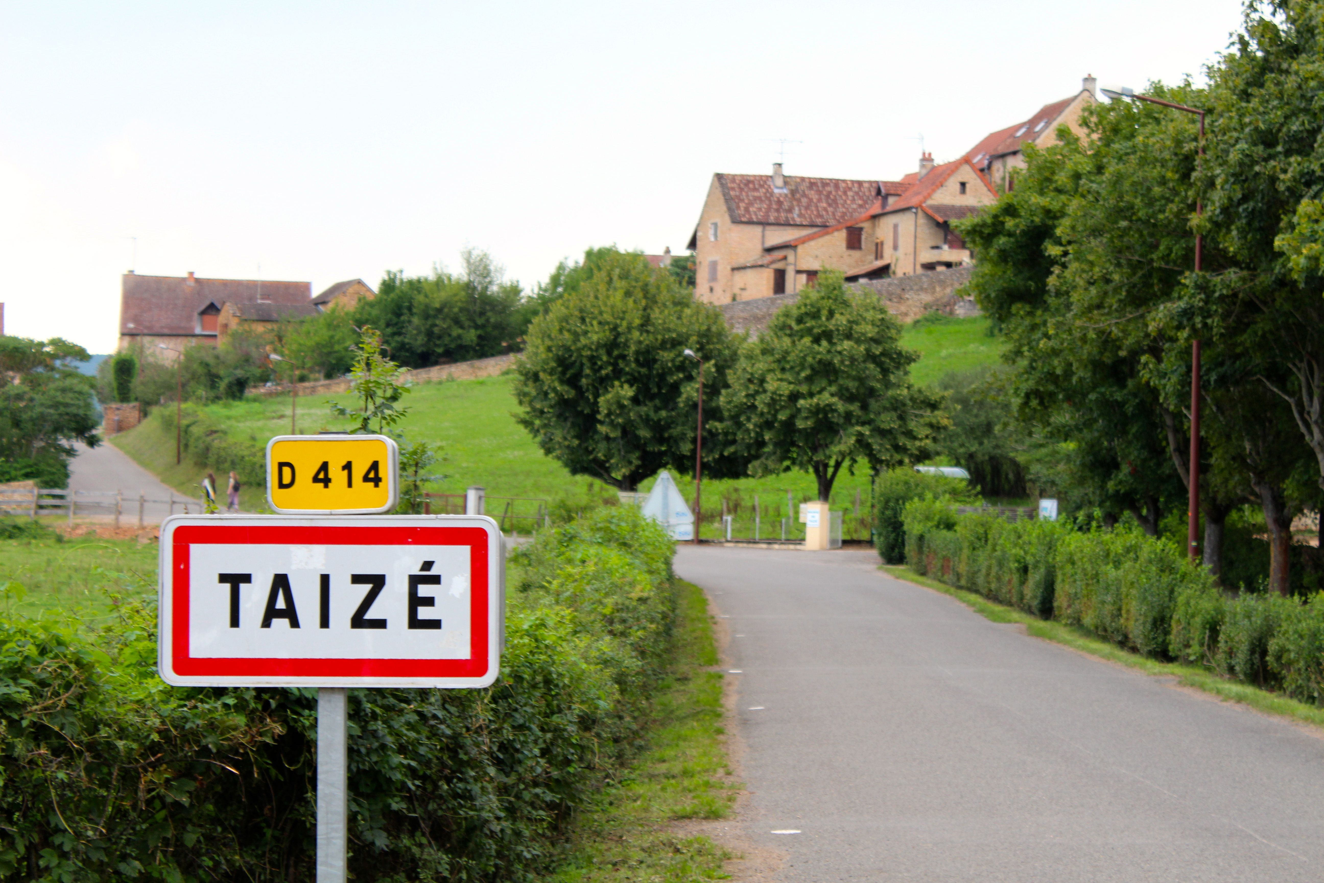 En mindre landsväg i Frankrike med en skylt med ortsnamnet Taizé.
