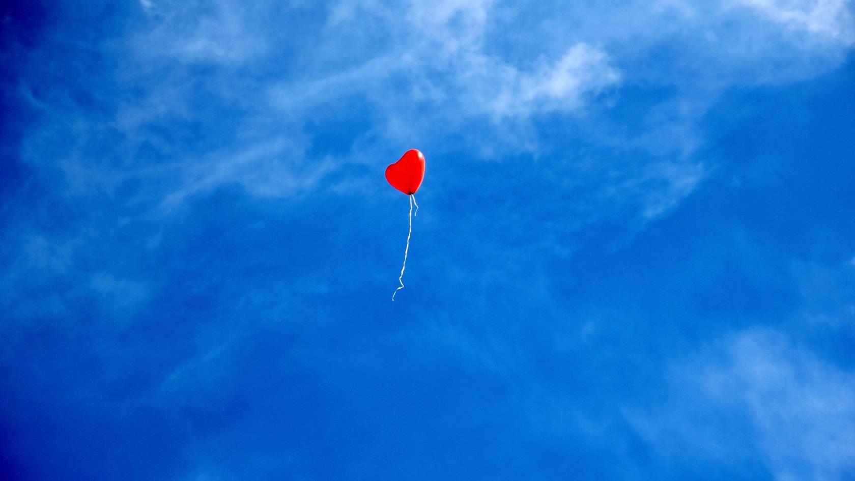 Röd ballong på blå himmel