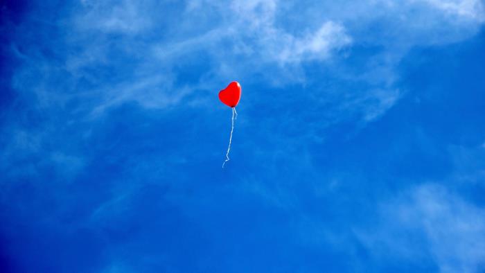 Röd ballong på blå himmel
