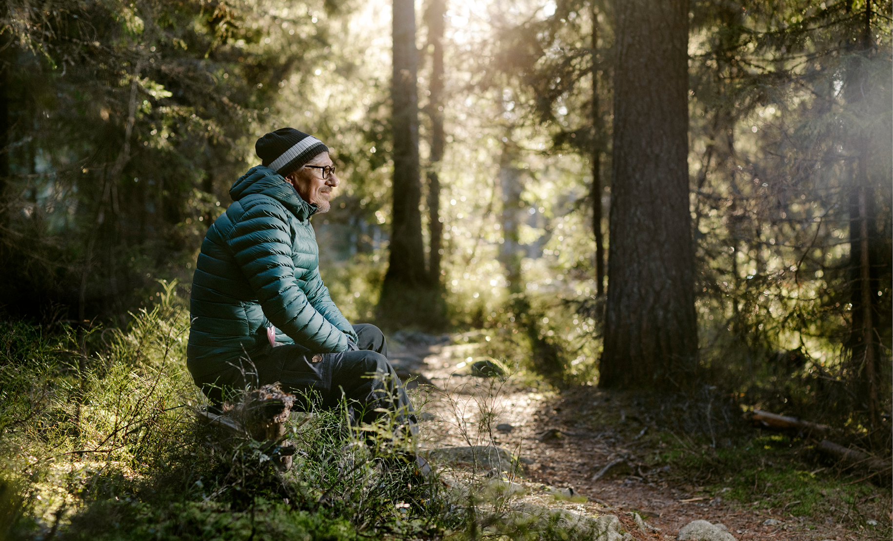 Man sitter i skogsglänta