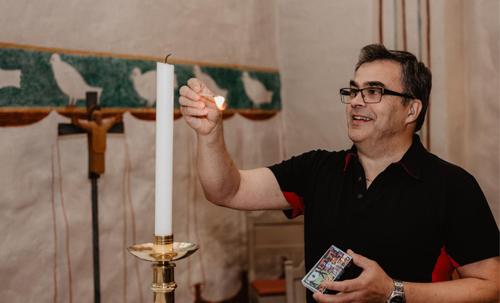 Vaktmästare Anders Lundmark tänder ett ljus i Backens kyrka.