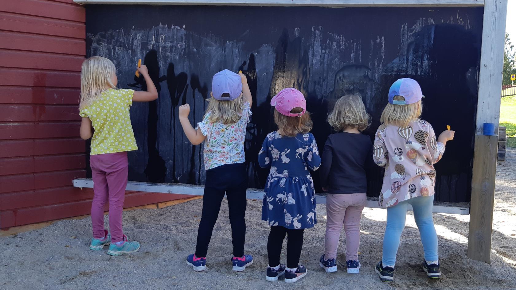 Barn står och ritar mot en vägg
