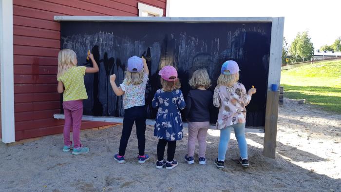 Barn står och ritar mot en vägg