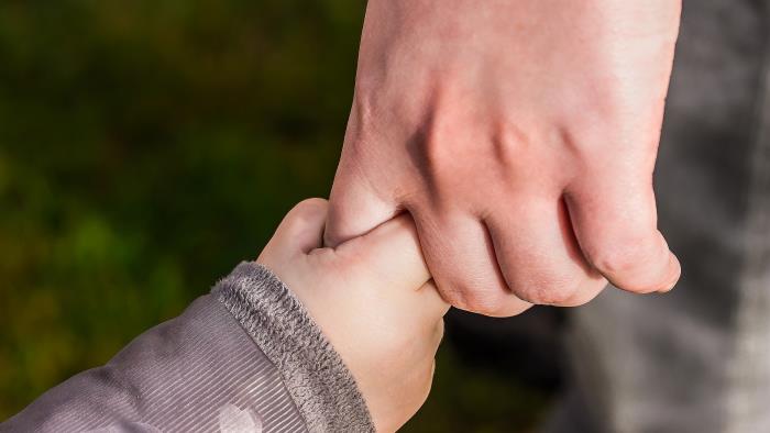 En barnhand som håller i en vuxen hand