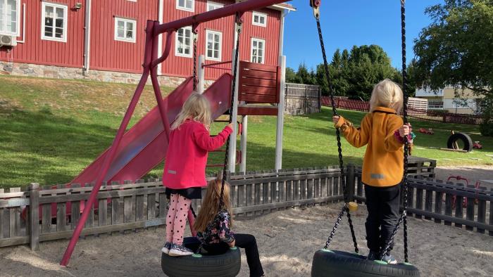 Förskolebarn gungar utomhus