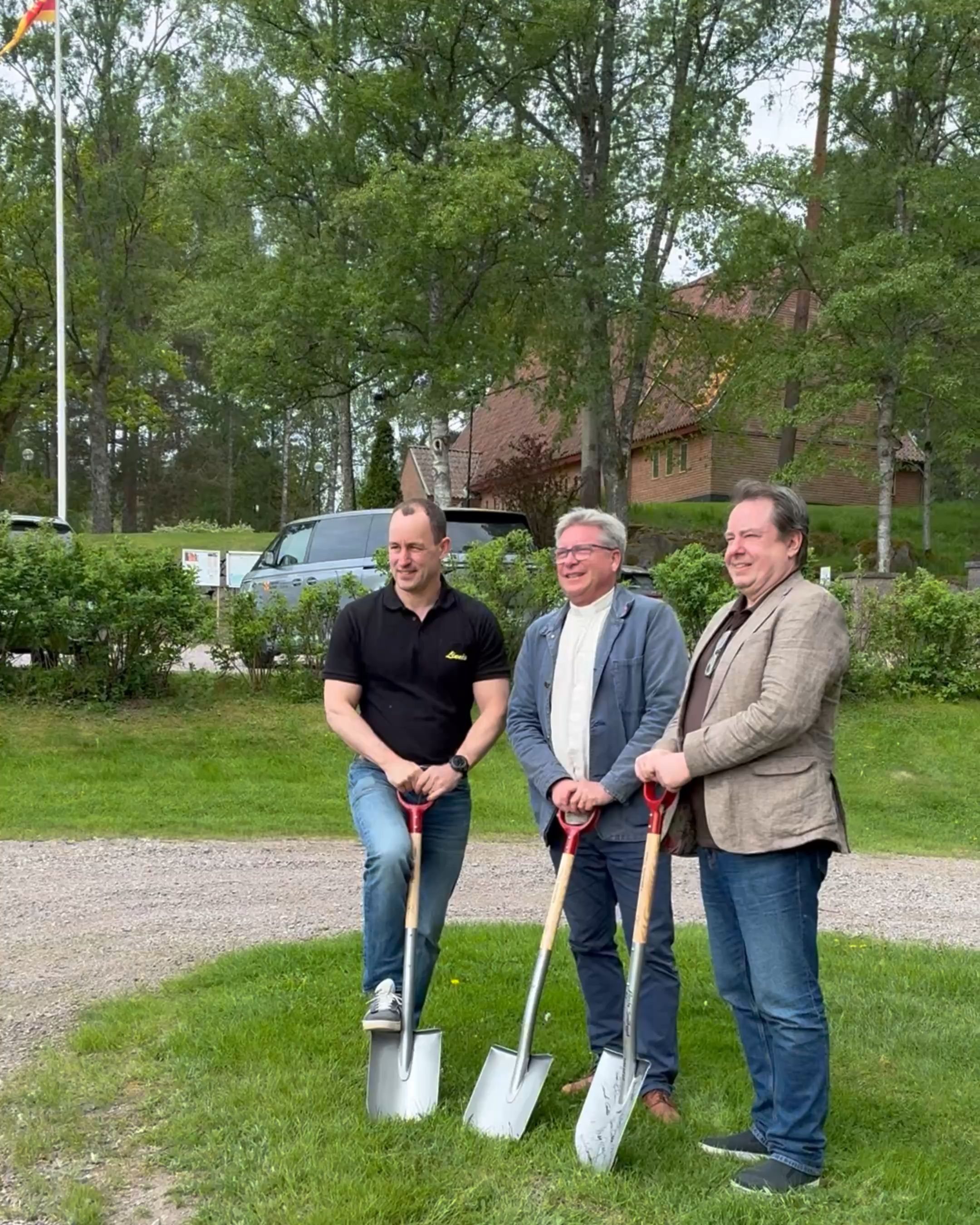 Tre män håller varsin spade framför Björneborgs kyrka.