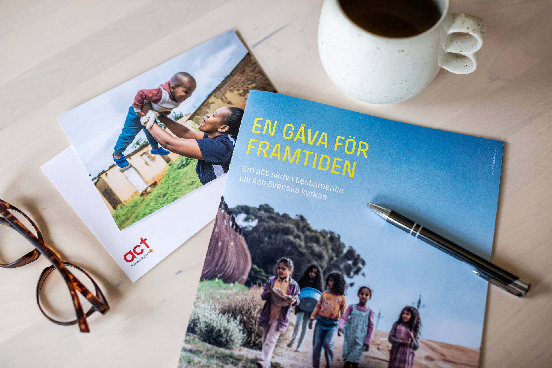 Penna, glasögon och en folder för att skriva testamente ligger på ett bord. 