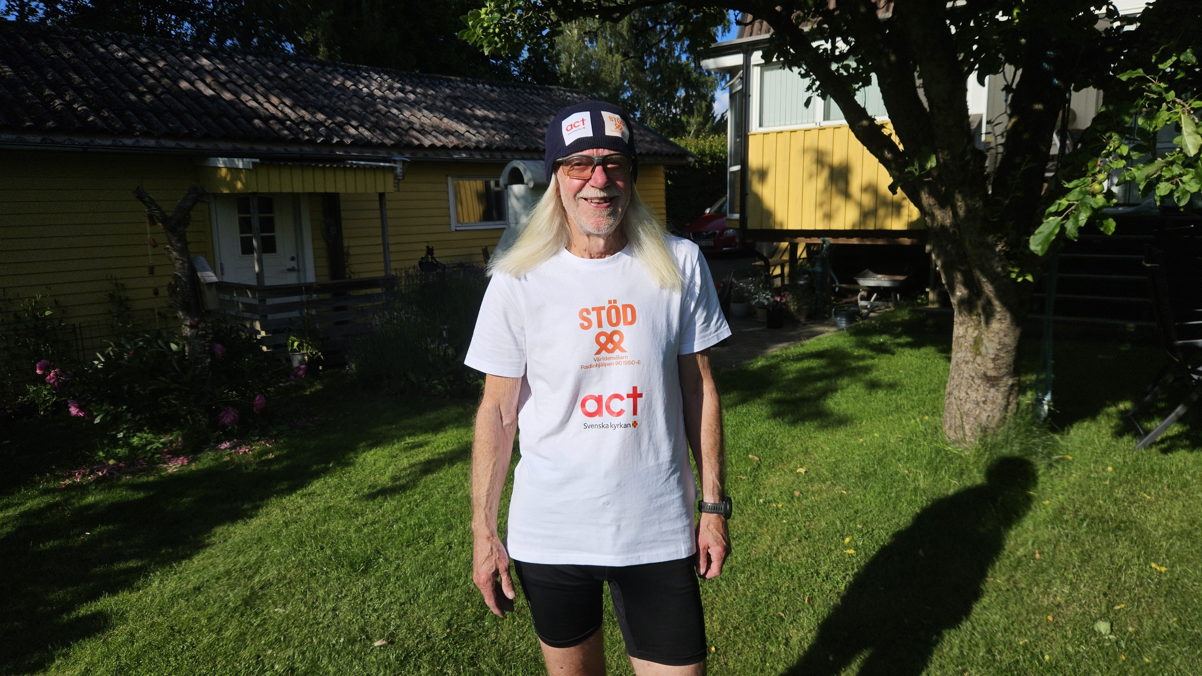 En man tittar mot kameran och ler. Han har springkläder och mössa på sig. 