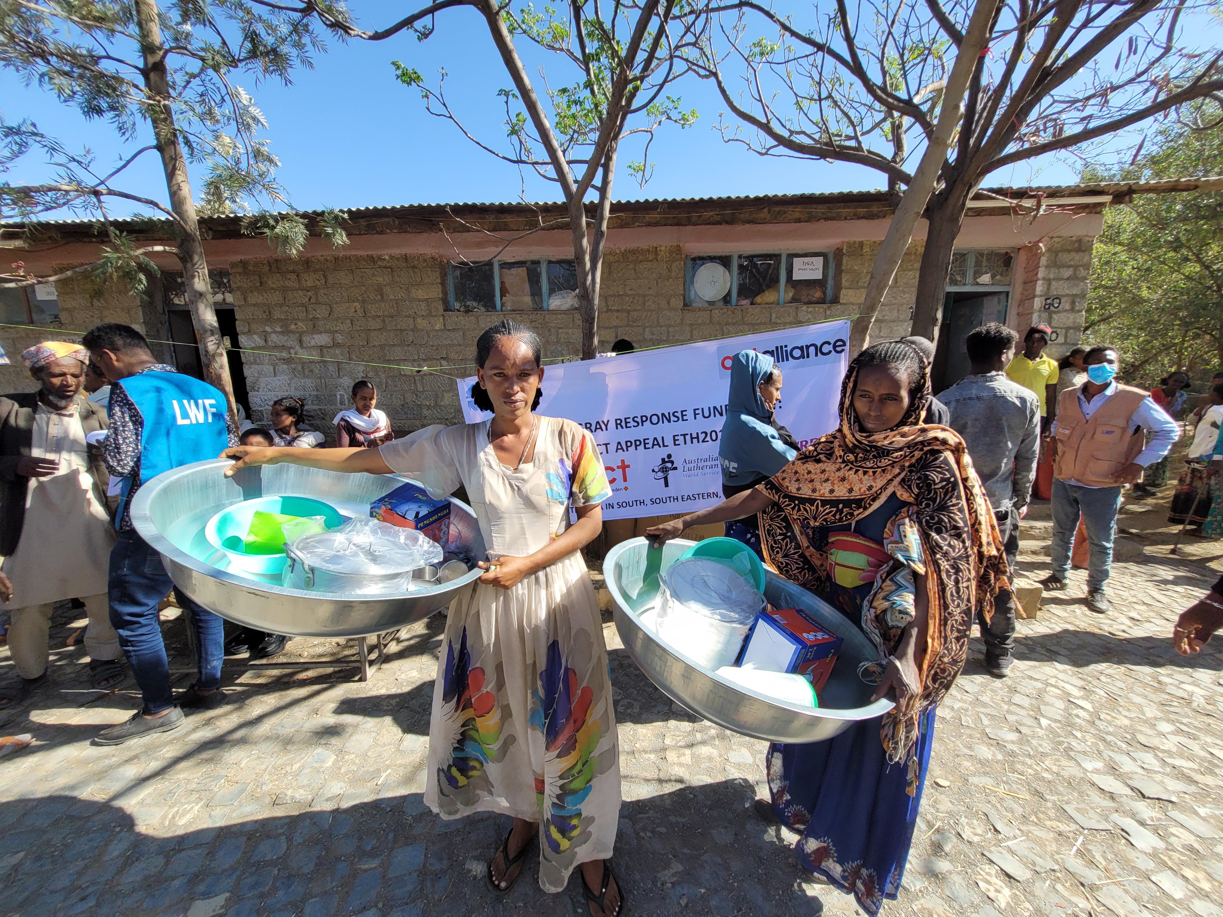 Två kvinnor som håller i sina köksutrustningskit som de har fått vid utdelningen av köksutrustning i Etiopien.