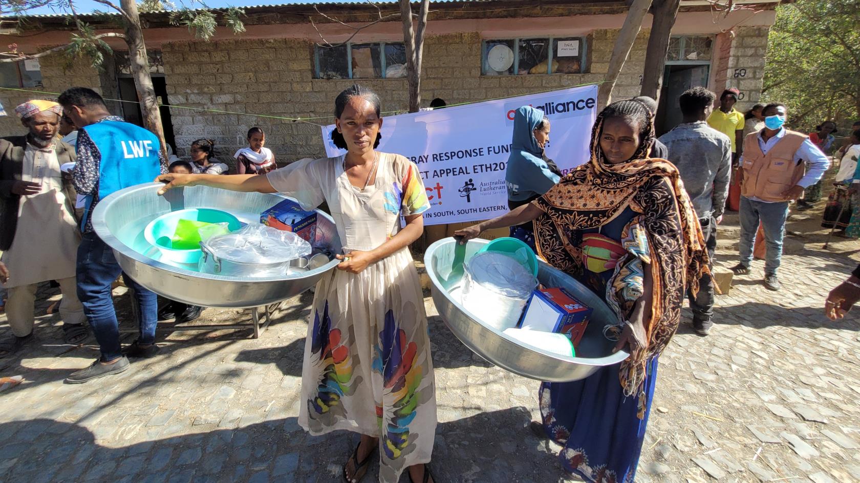 Två kvinnor som håller i sina köksutrustningskit som de har fått vid utdelningen av köksutrustning i Etiopien.