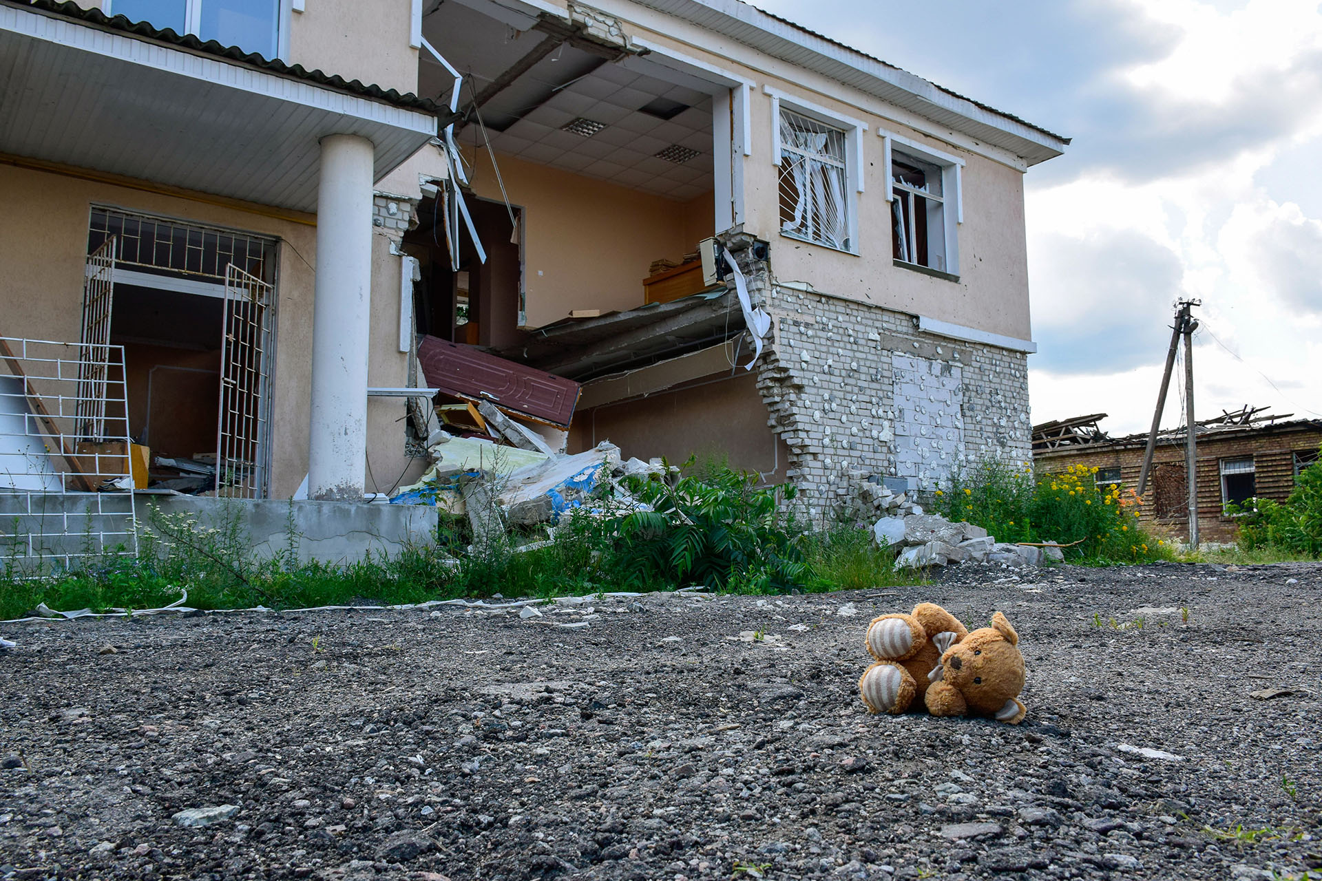 Bild på ett hus som träffats av en sprängladdning med ett mjukisdjur liggande på marken framför huset. 