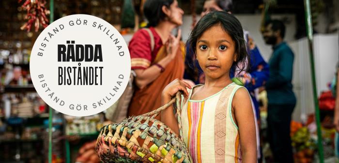 Flicka på en marknad i Indien. På bilden ligger logotypen för Rädda biståndet. 