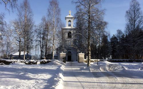 Kyrka i bakgrunden, i snölandskap med blå himmel. 