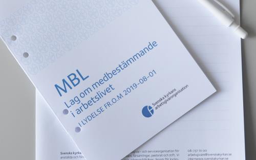 Ett häfte med rubriken MBL Lag om medbestämmande i arbetslivet ligger ovanpå ett anteckningsblock på ett bord