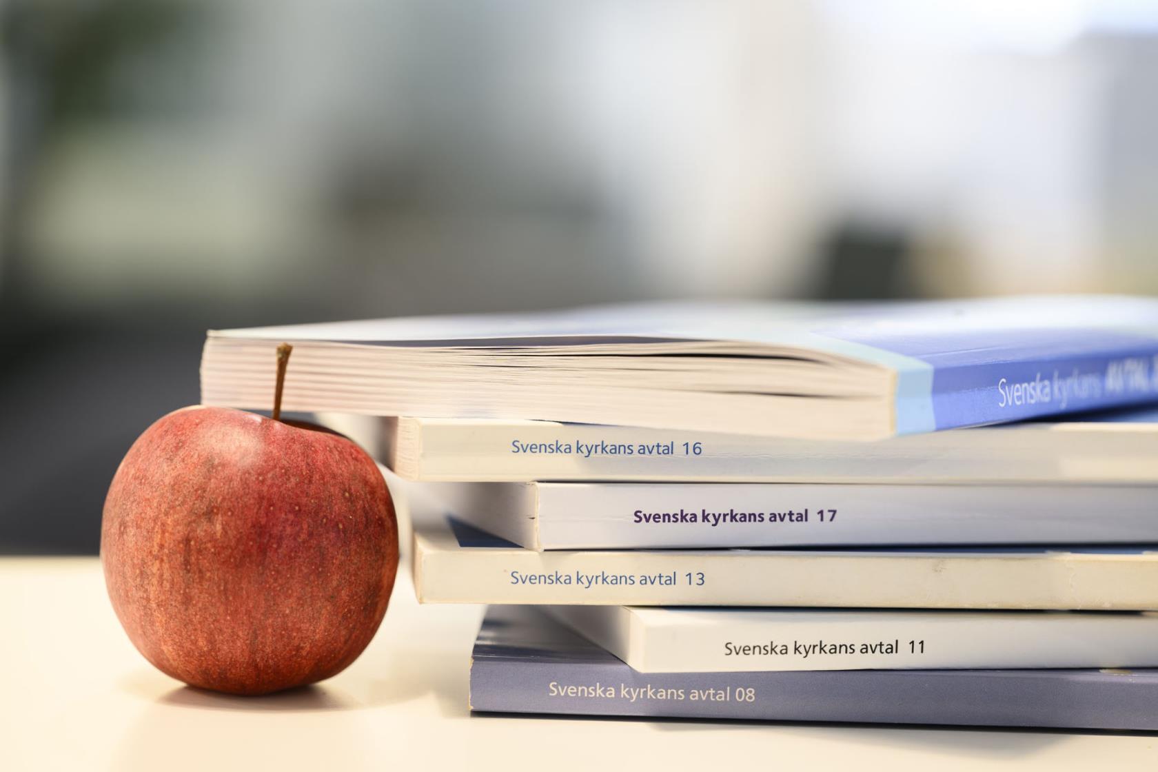 ett antal avtalsböcker i en trave intill ett äpple. 
