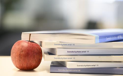 ett antal avtalsböcker i en trave intill ett äpple. 