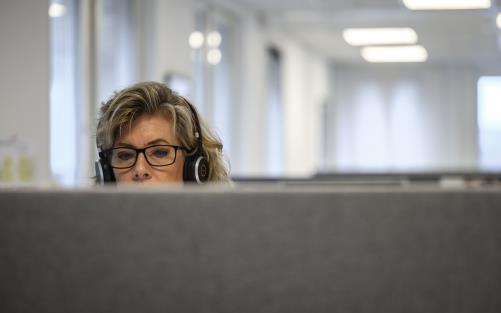 Kvinna med glasögon och hörlurar syns bakom en ljuddämpande skärm.