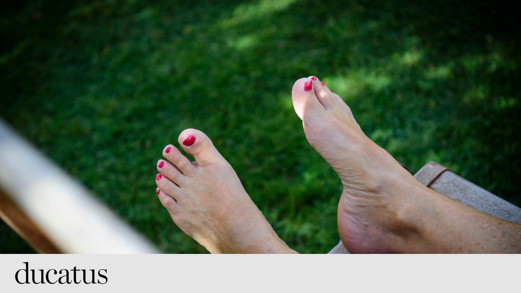 Två fötter med målade tånaglar mot en fond av grön gräsmatta. 