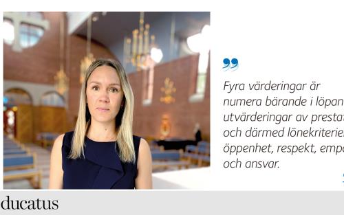 Kvinna med mörk blus står i kyrkorum. 