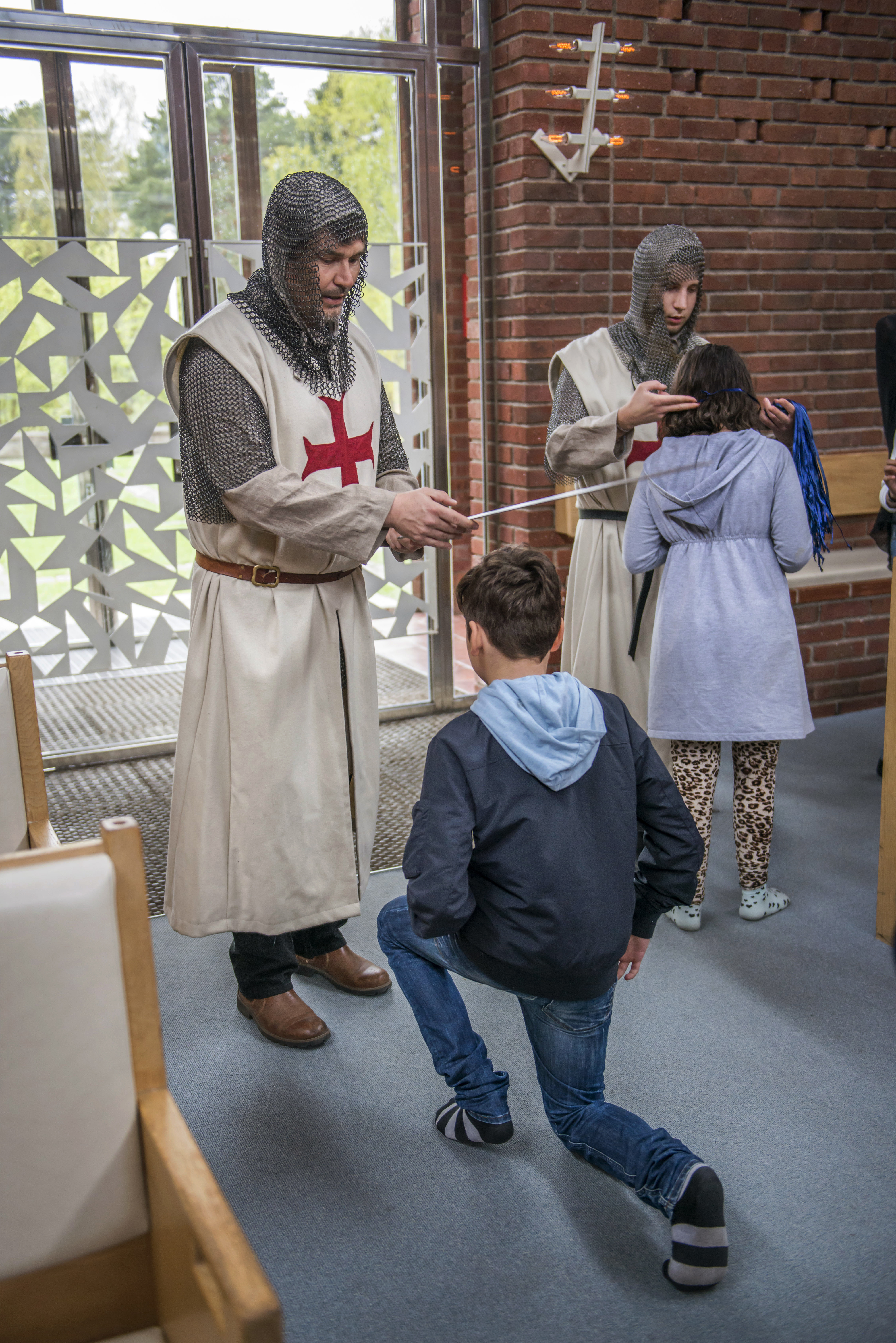 En riddare dubbar en elev under riddarskolan.