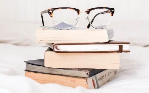 En hög med böcker med glasögon på toppen. 