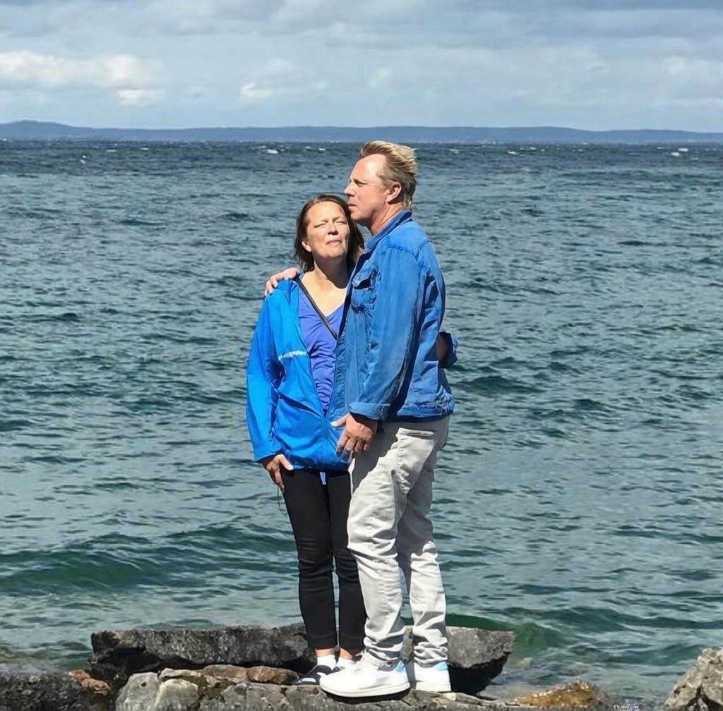 En man och en kvinna står vid havet och håller om varandra