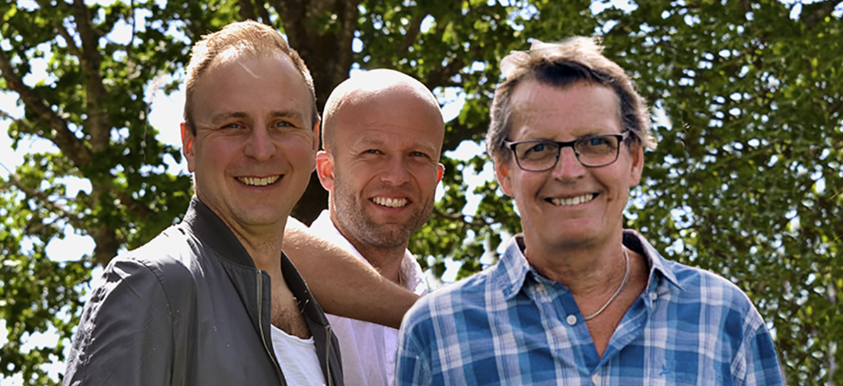 Trio av glada män i sommarsolen