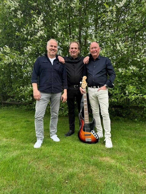 Tre män står i sommargrönska