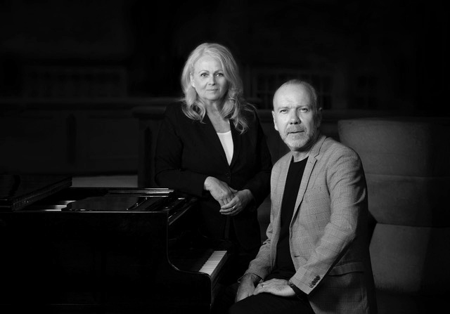 Svartvit bild på kvinna och man vid piano