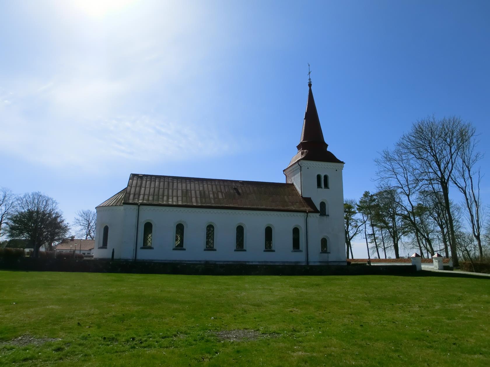 En vit kyrka med rött tegeltak och kyrktorn.