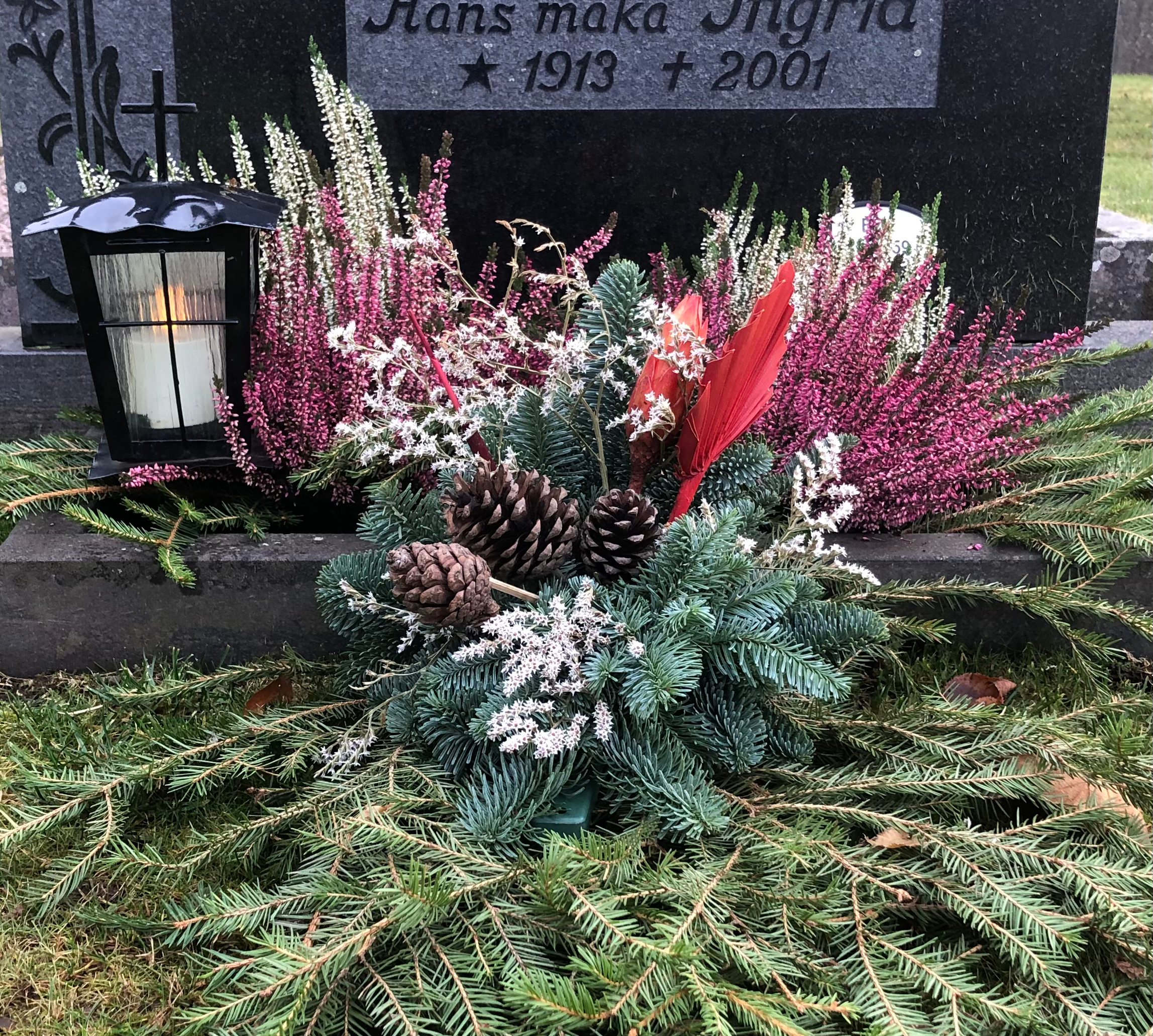 En grav med en tänd lykta, ljung, granris och kottar