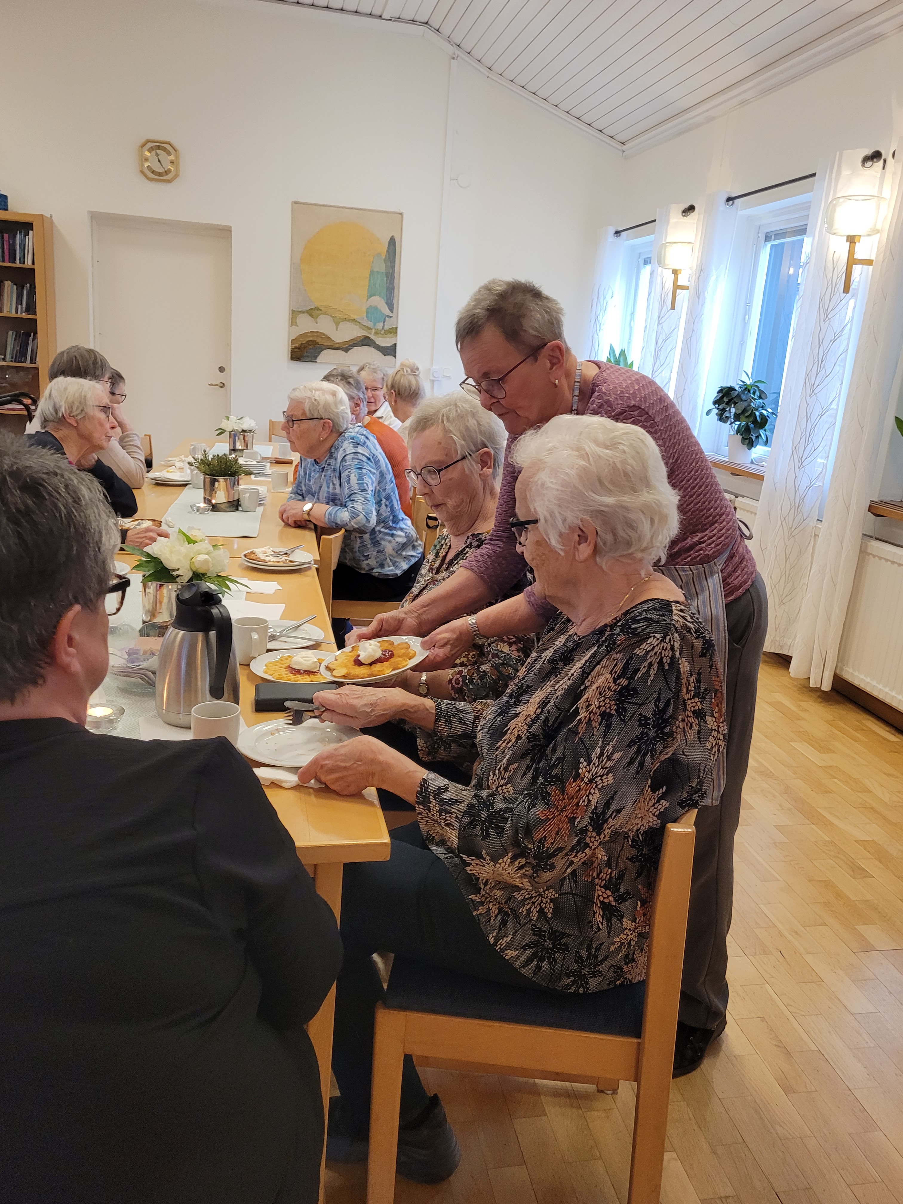 Glada damer blir serverade våfflor av volontär