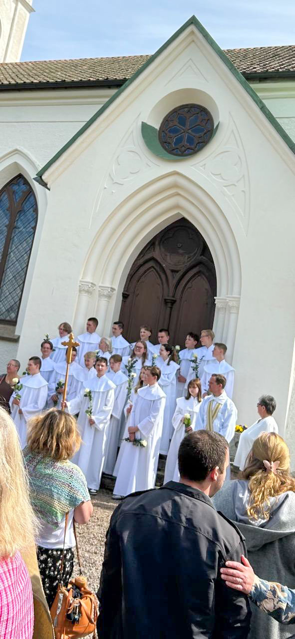 Konfirmander står på kyrktrappan efter konfirmationen