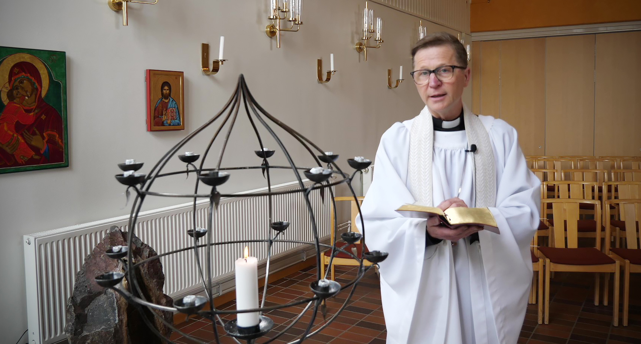 Prästen Kjell Gustafsson står vid ljusbäraren i Öxnehagakyrkan