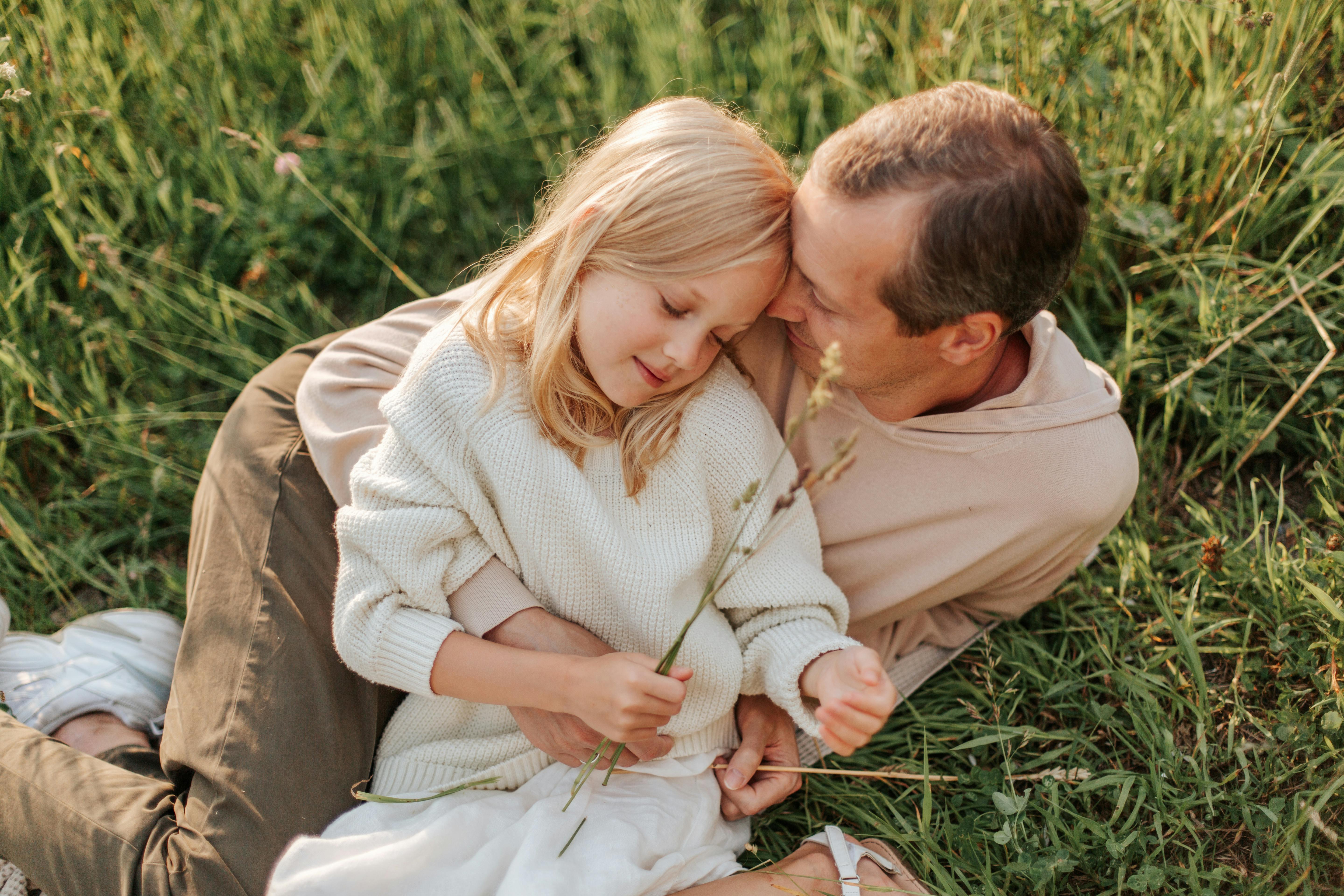 En far och yngre dotter kramas på en äng