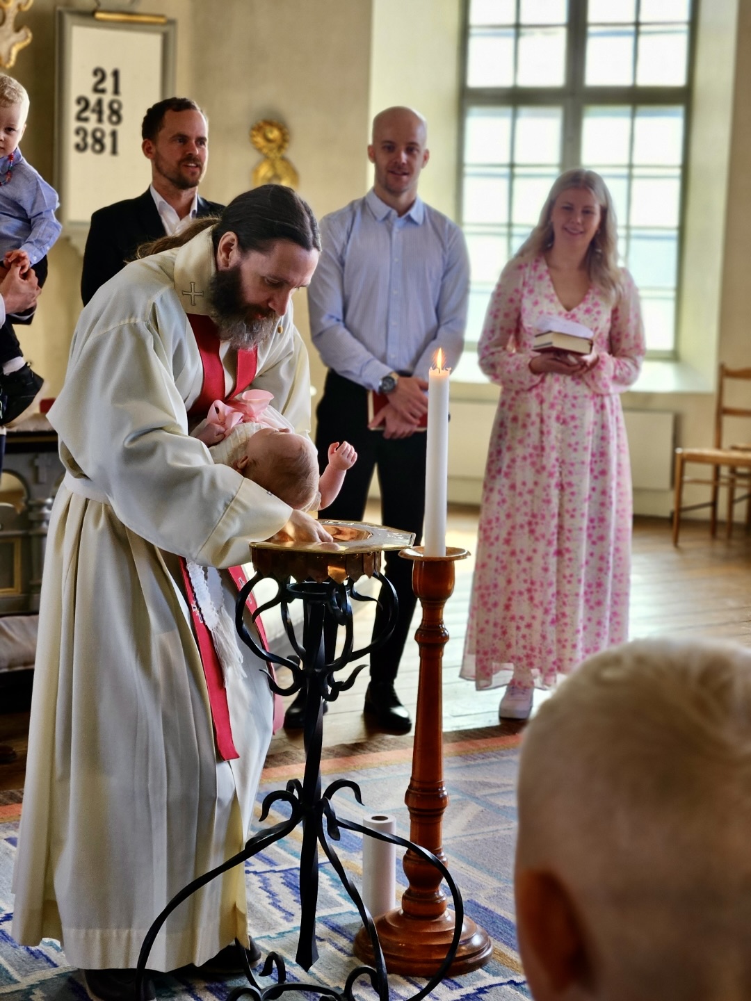 En bebis döps i Amnehärads kyrka med familj och släkt omkring sig