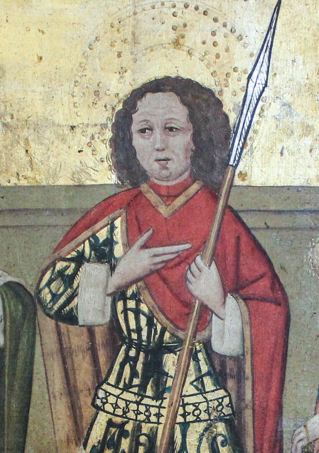 Närbild på gestalt med spjut och röd mantel.