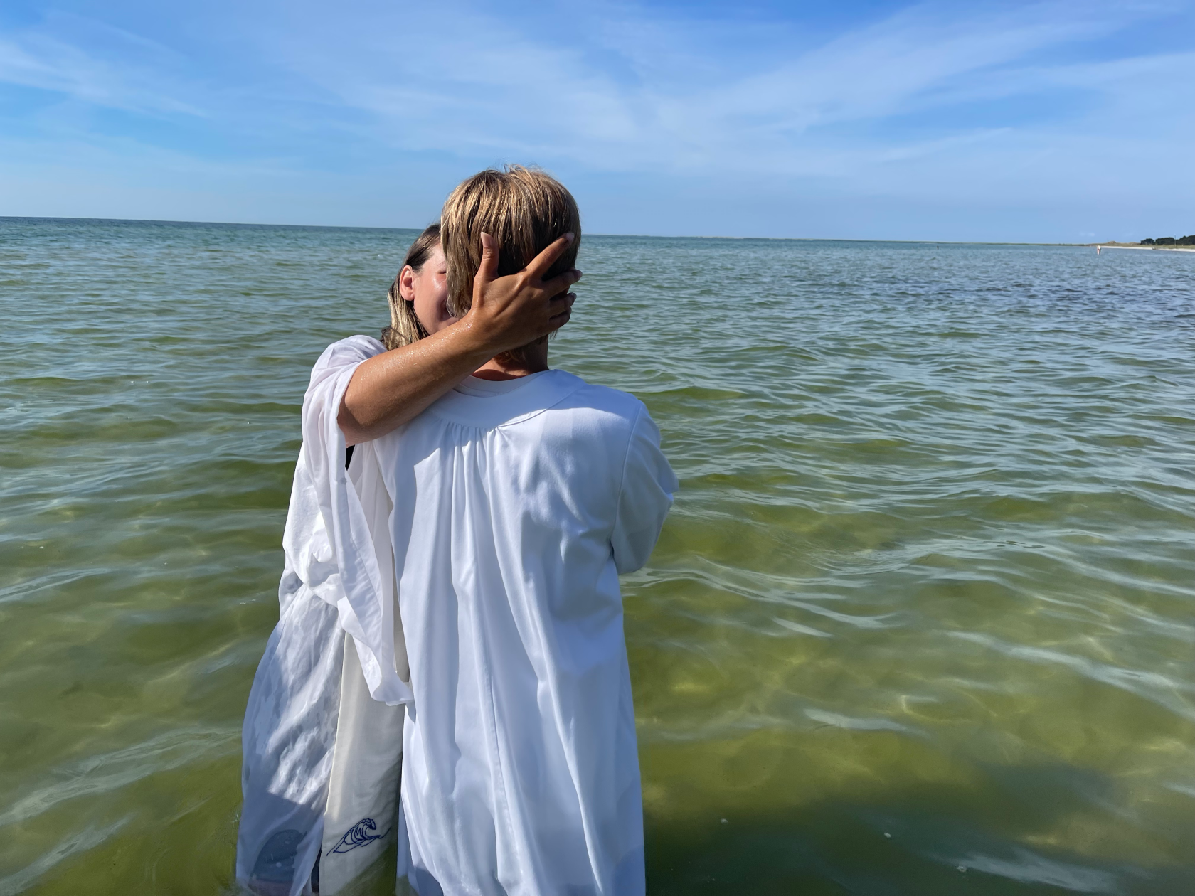 Präst döper blivande konfirmand i havet. 