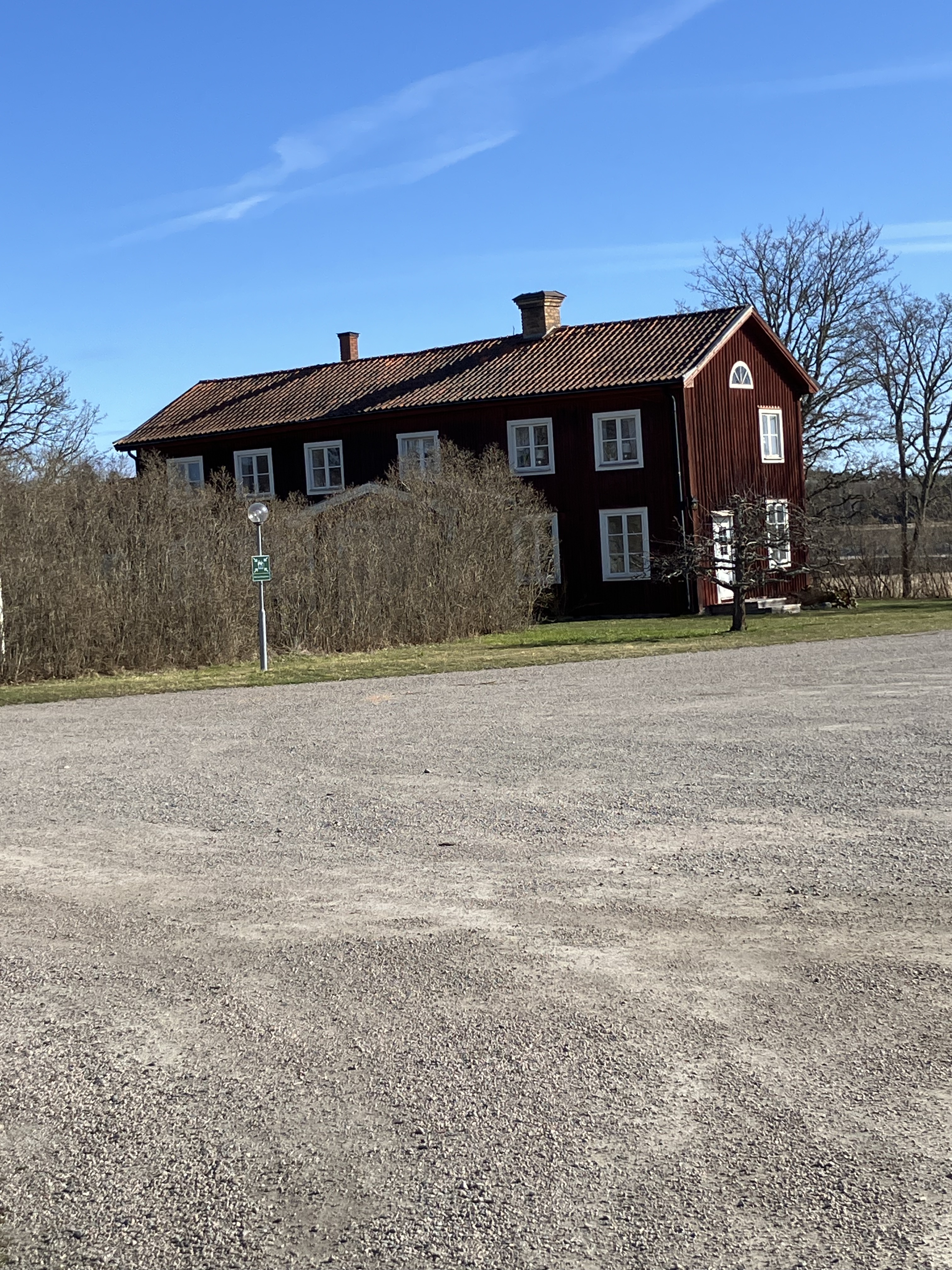 Ett rött tvåvåningshus delvis täckt av en syrénhäck