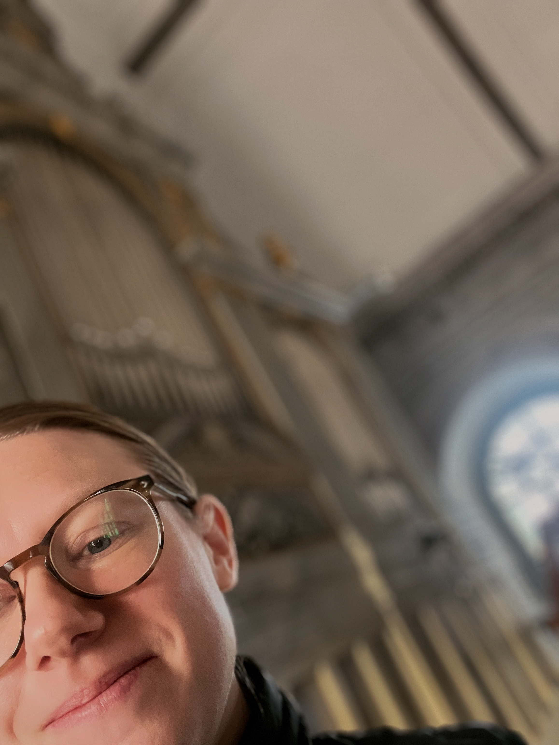 Bild på kvinna som tittar fram i hörnet av bilden framför en orgel.