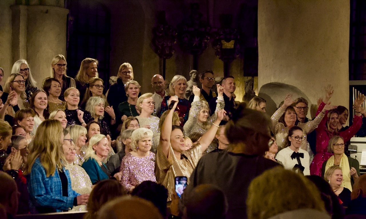 Kör med kvinnor och män som sjunger gospel. Glittriga kläder uppsträckta händer.