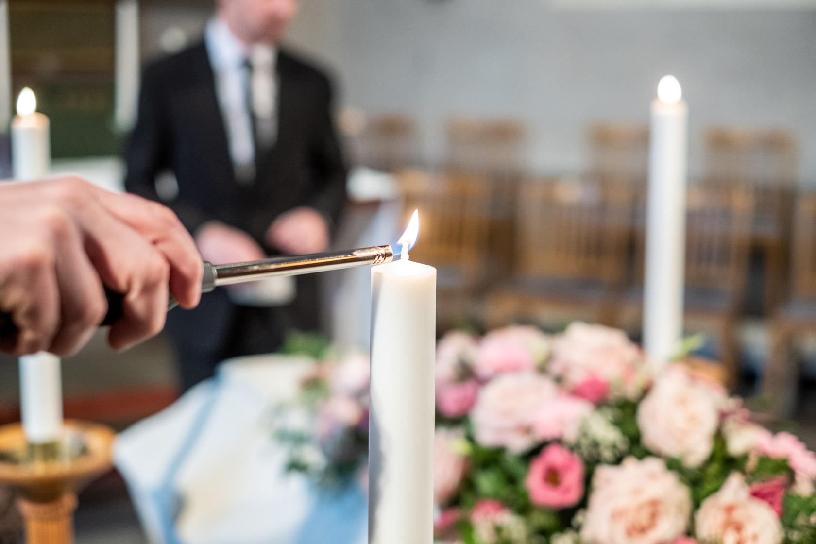 Bild på kista med rosa blommor och ljus som tänds runt om.