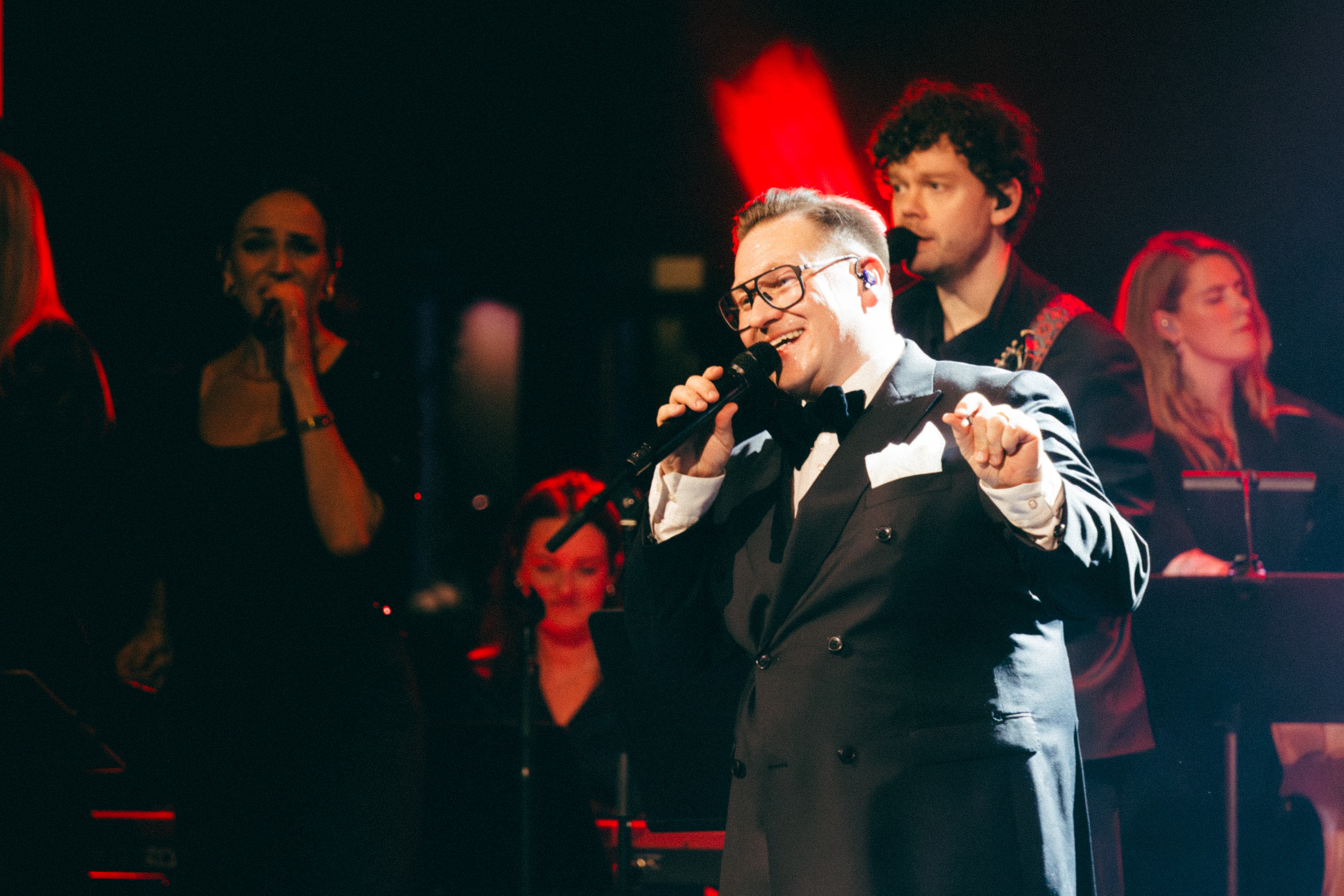 Man står med mick och sjunger med röd lampa på sig.