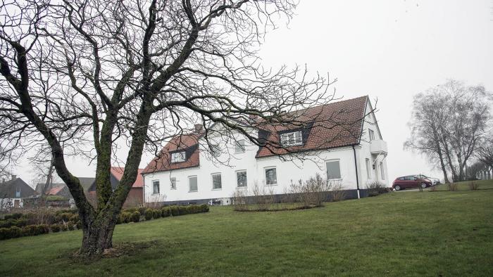 Bilden föreställer ett stort vitt hus med rött tegeltak.