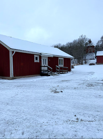 Ett lågt, rött hus omgivet av snö.