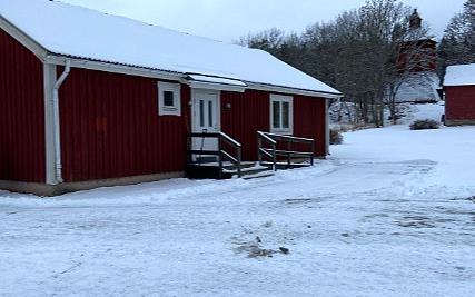 Ett lågt, rött hus omgivet av snö.