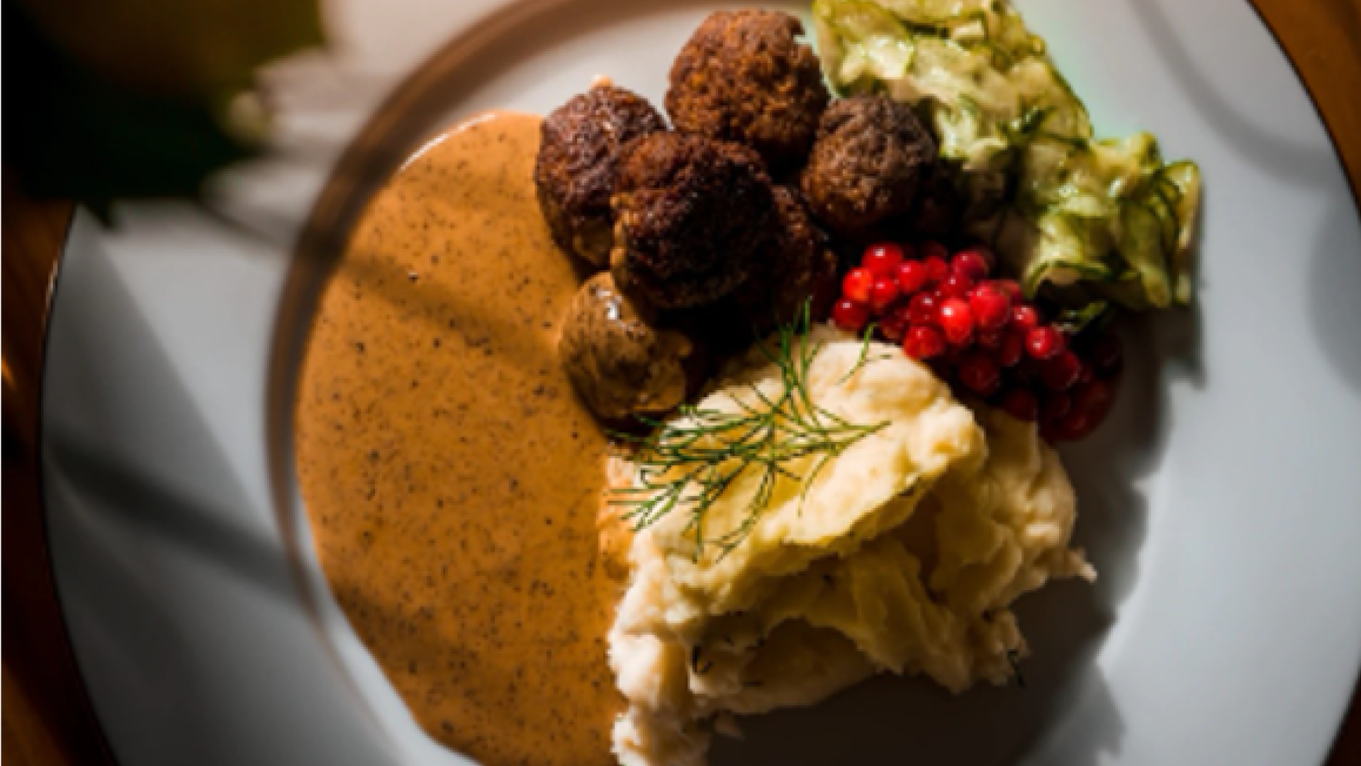 En tallrik med köttbullar, potatismos, brunsås och lingon.